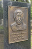Bronze plaque with a portrait and dates on a stone wall in a cemetery