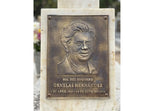 Bronze plaque with a portrait and engraved text on a marble base.