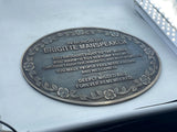 Memorial plaque on a car window honoring Brigitte Manspeaker with engraved text.