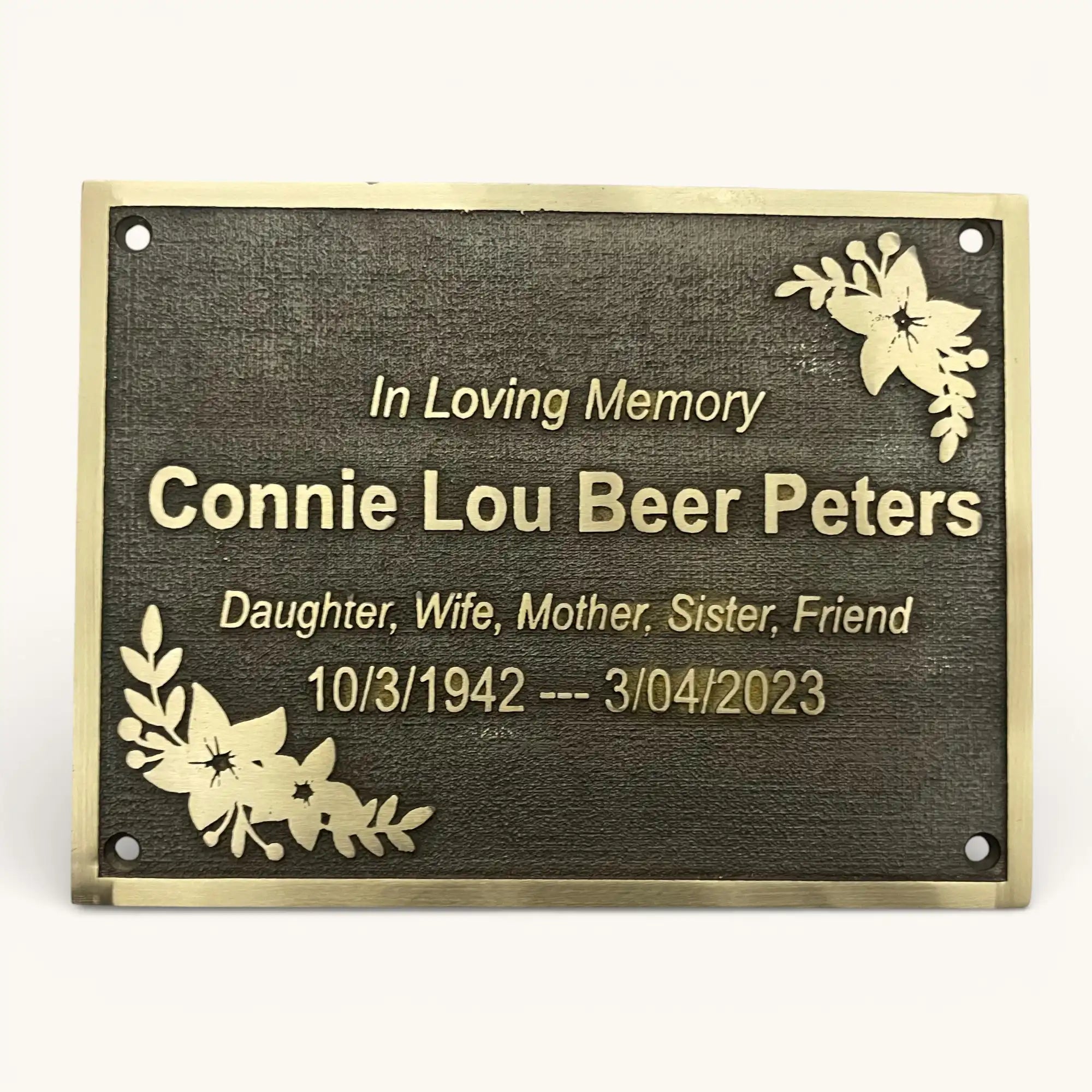 Memorial plaque with engraved text and floral designs on a white background