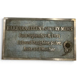 A rectangular bronze memorial plaque with engraved text reading 'BARBARA ELLEN LOWERY MIMS' and 'Born September 8, 1931 Beloved Daughter, Sister, Aunt and Mother,' plus an embossed sunflower design, shown on a plain white background.