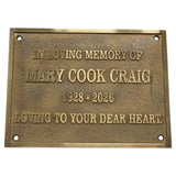 A rectangular bronze memorial plaque with raised lettering that reads 'IN LOVING MEMORY OF MARY COOK CRAIG 1928 - 2026 LOVING TO YOUR DEAR HEART' on a plain white background.