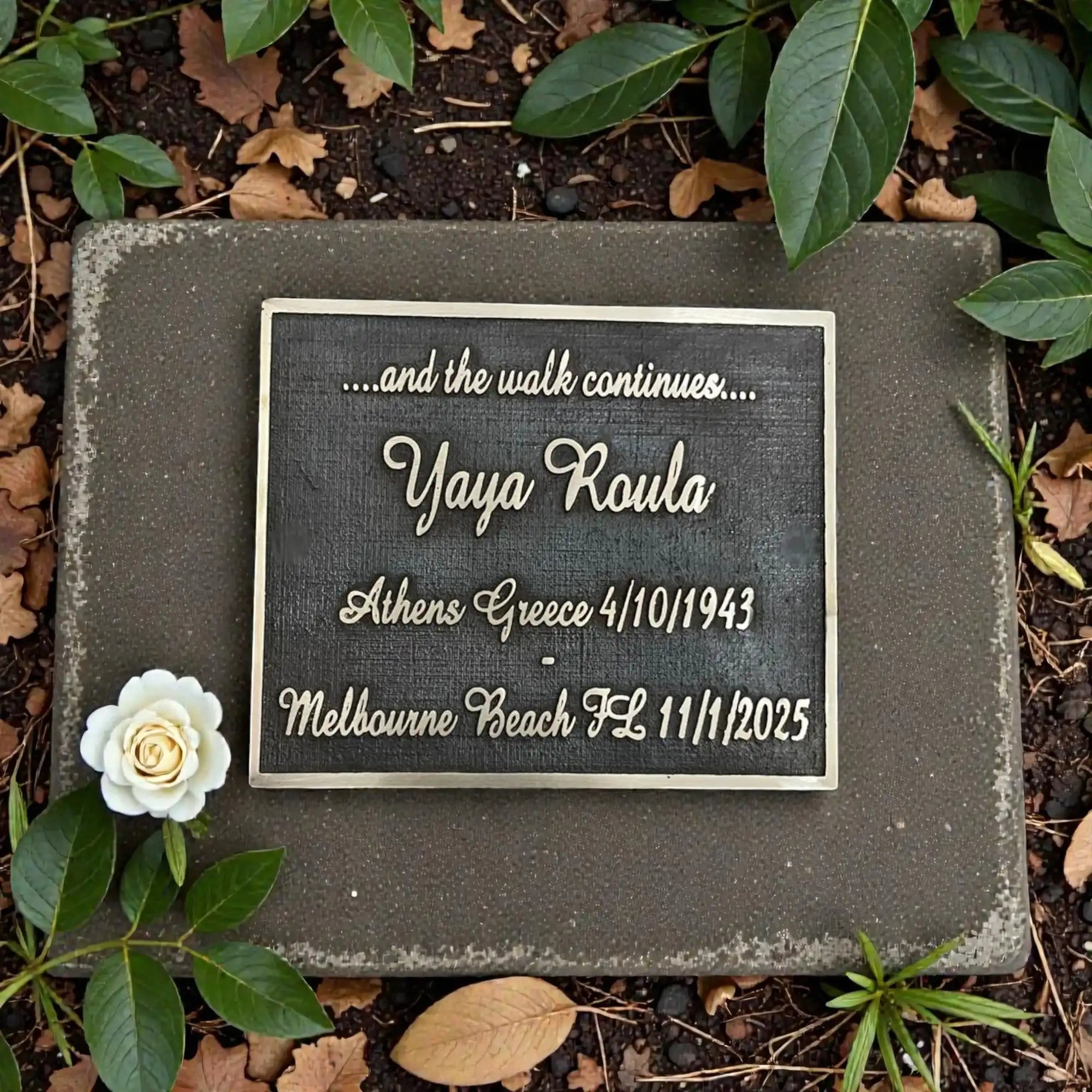 Memorial plaque with engraved text on a stone slab surrounded by plants and leaves.