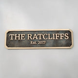 Brass house nameplate with 'THE RATCLIFFS Est. 2017' text on a gray background