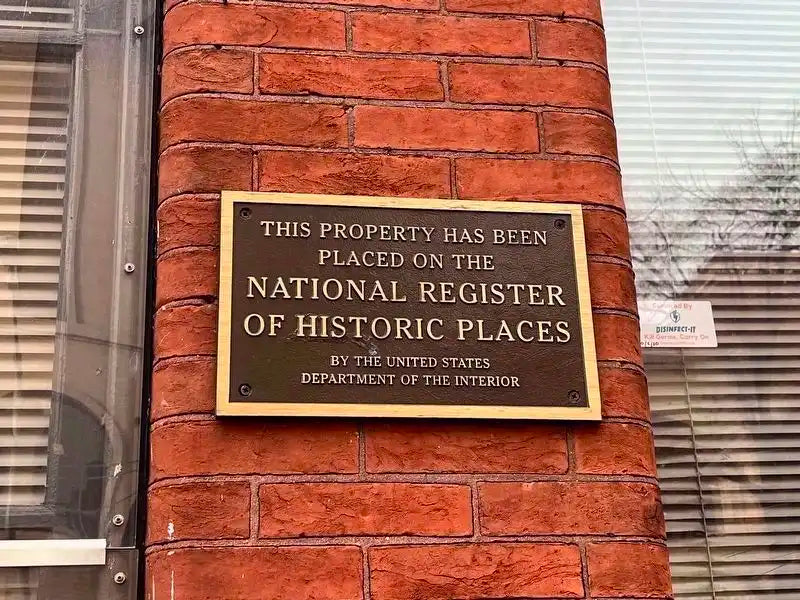Brass plaque on a brick wall indicating placement on the National Register of Historic Places.