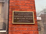 Brass plaque on a brick wall indicating placement on the National Register of Historic Places.