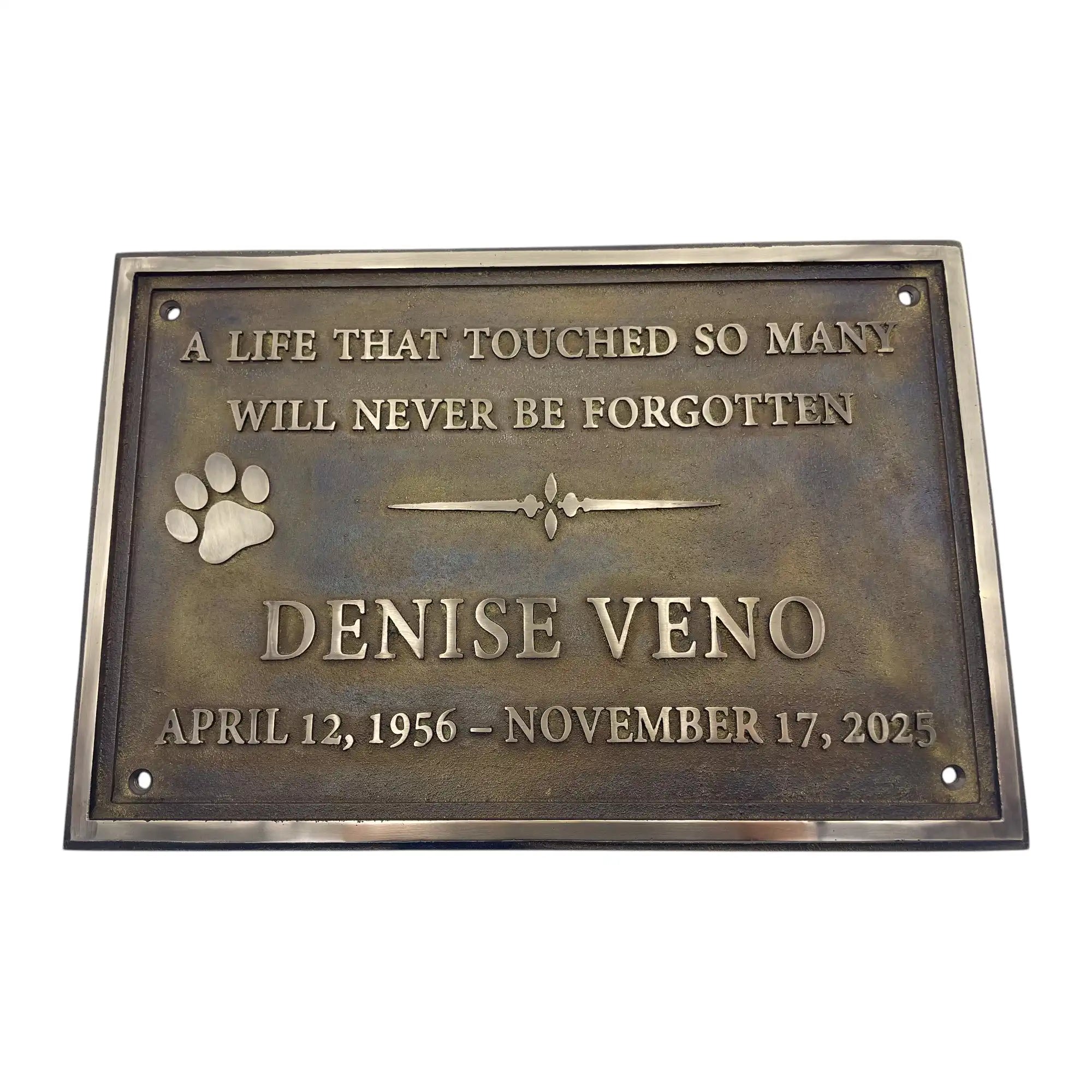 Bronze plaque with engraved text and paw print on a white background