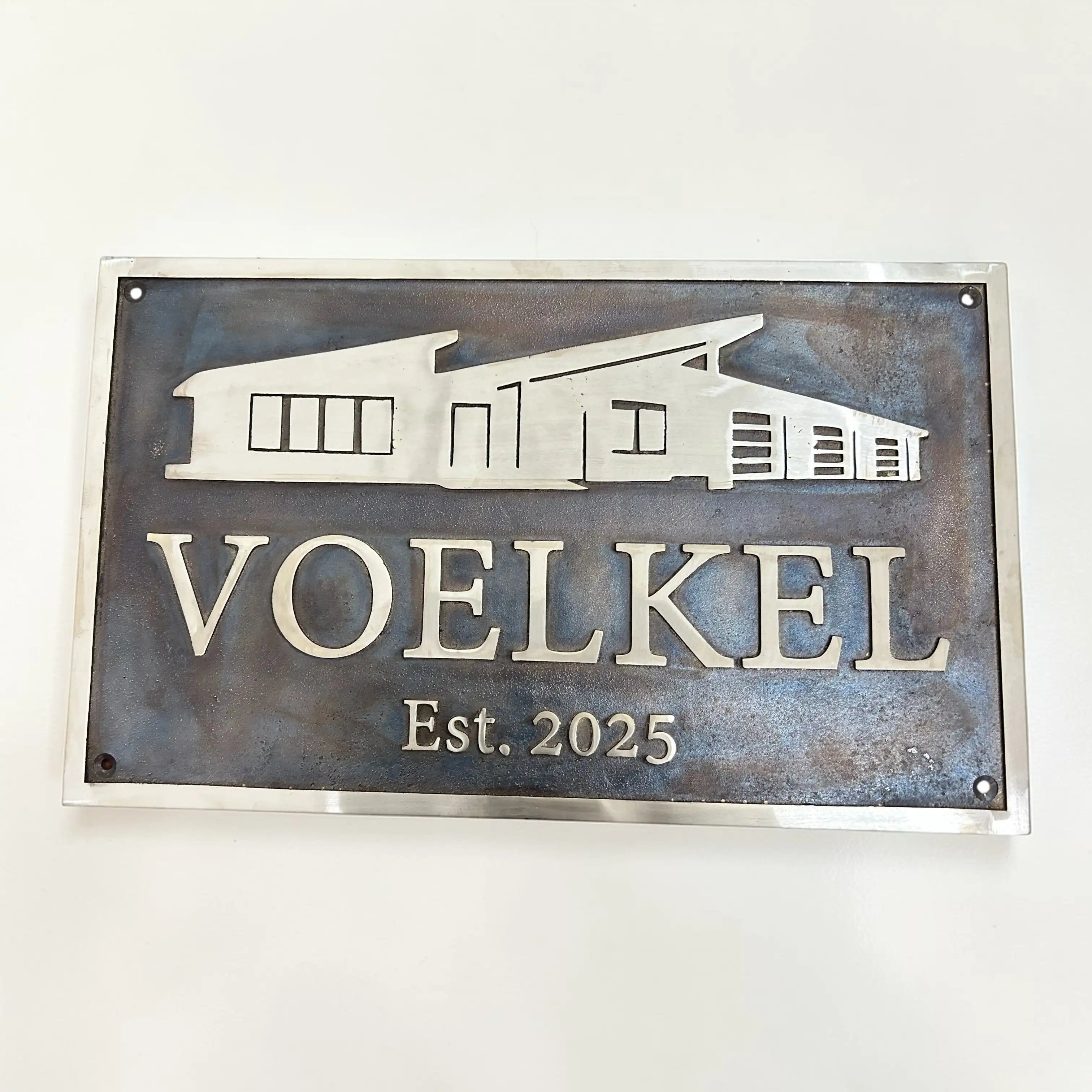 Bronze sign with house silhouette and 'VOELKEL Est. 2025' text on a white background