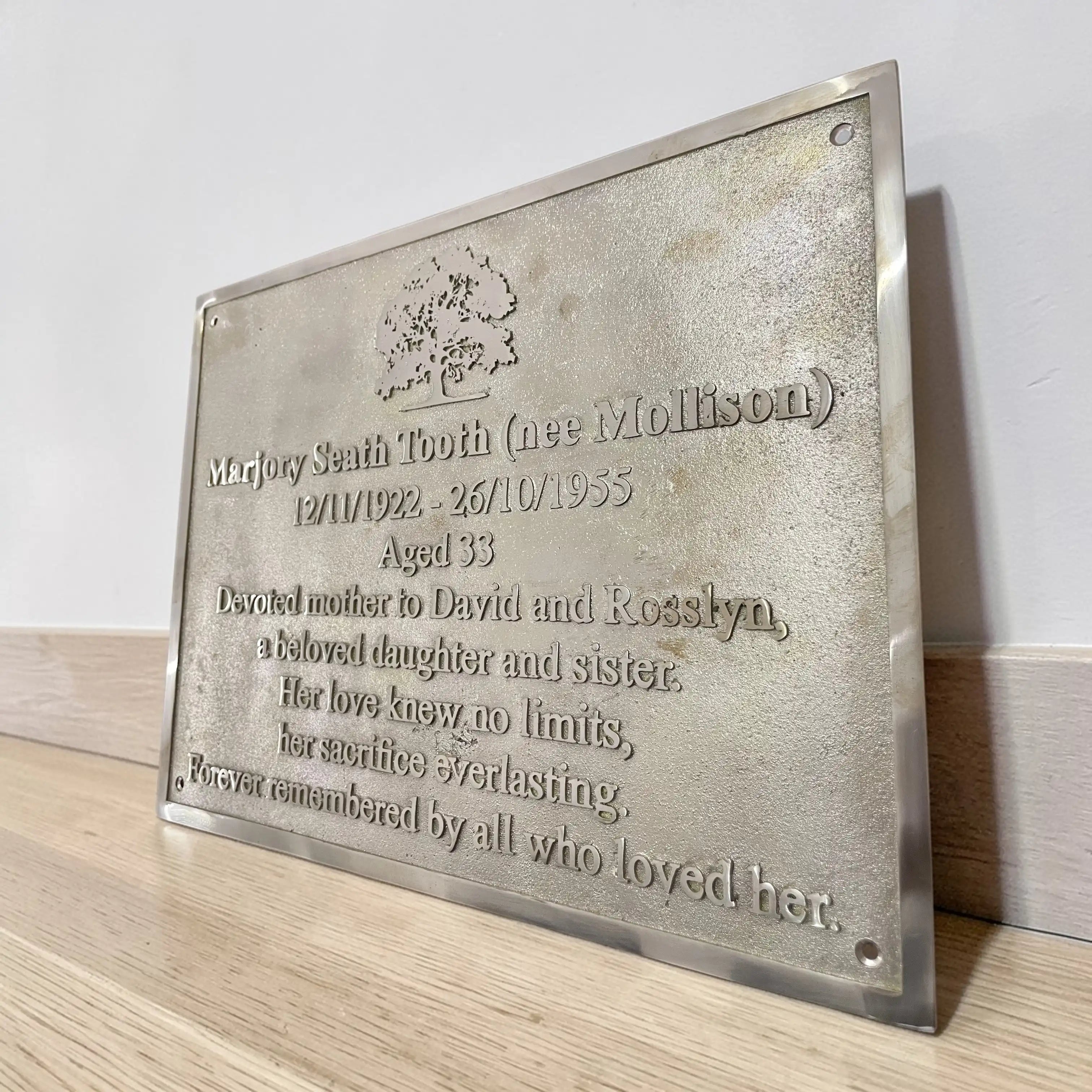 Brass memorial plaque with engraved text on a wooden surface