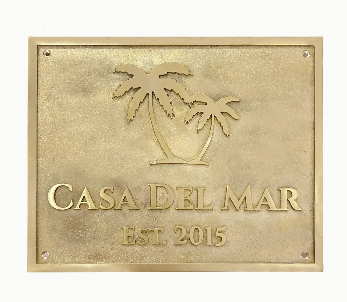Brass plaque with palm tree design and 'Casa Del Mar' text on a white background