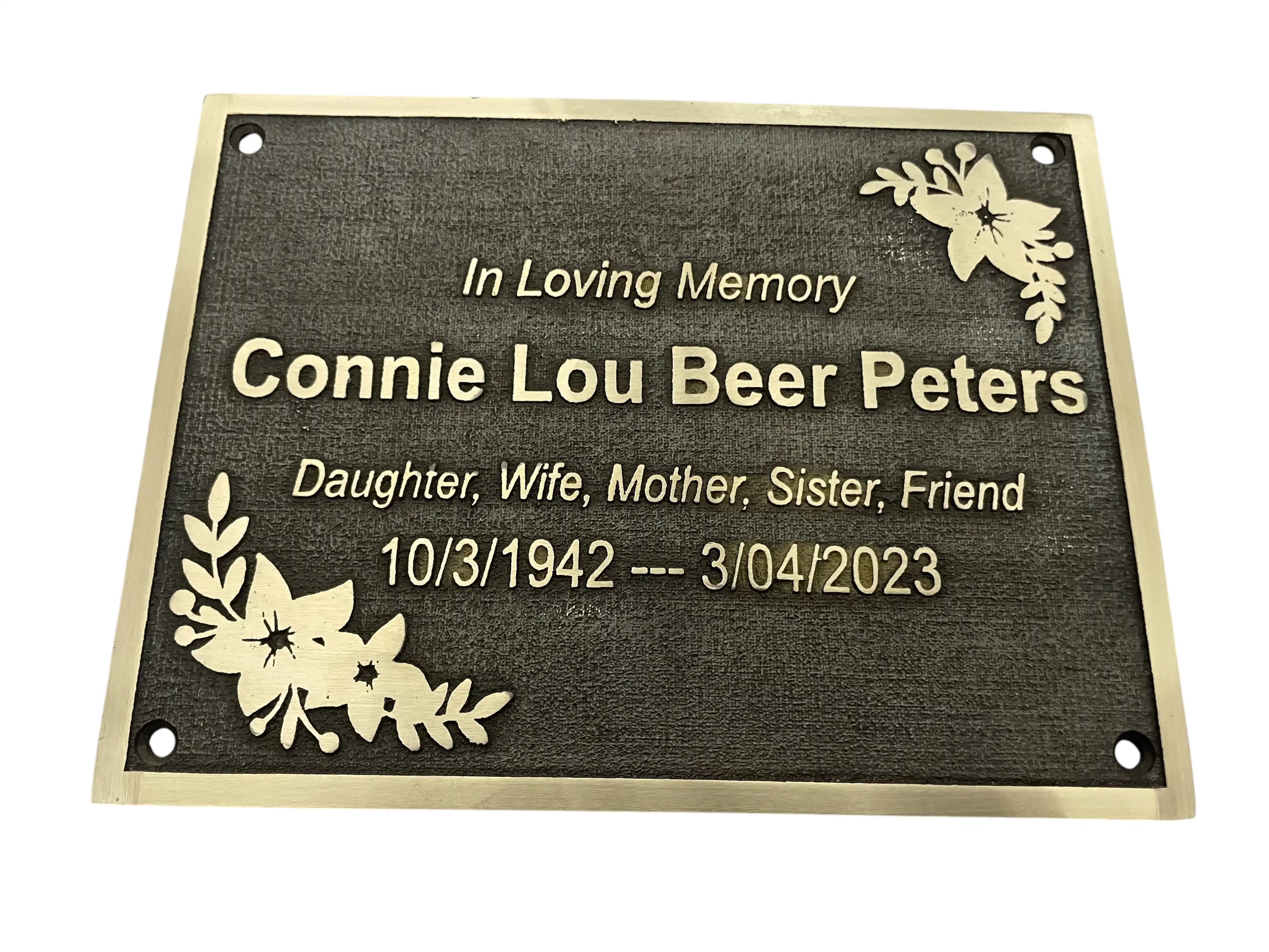 Memorial plaque with engraved text and floral designs on a white background