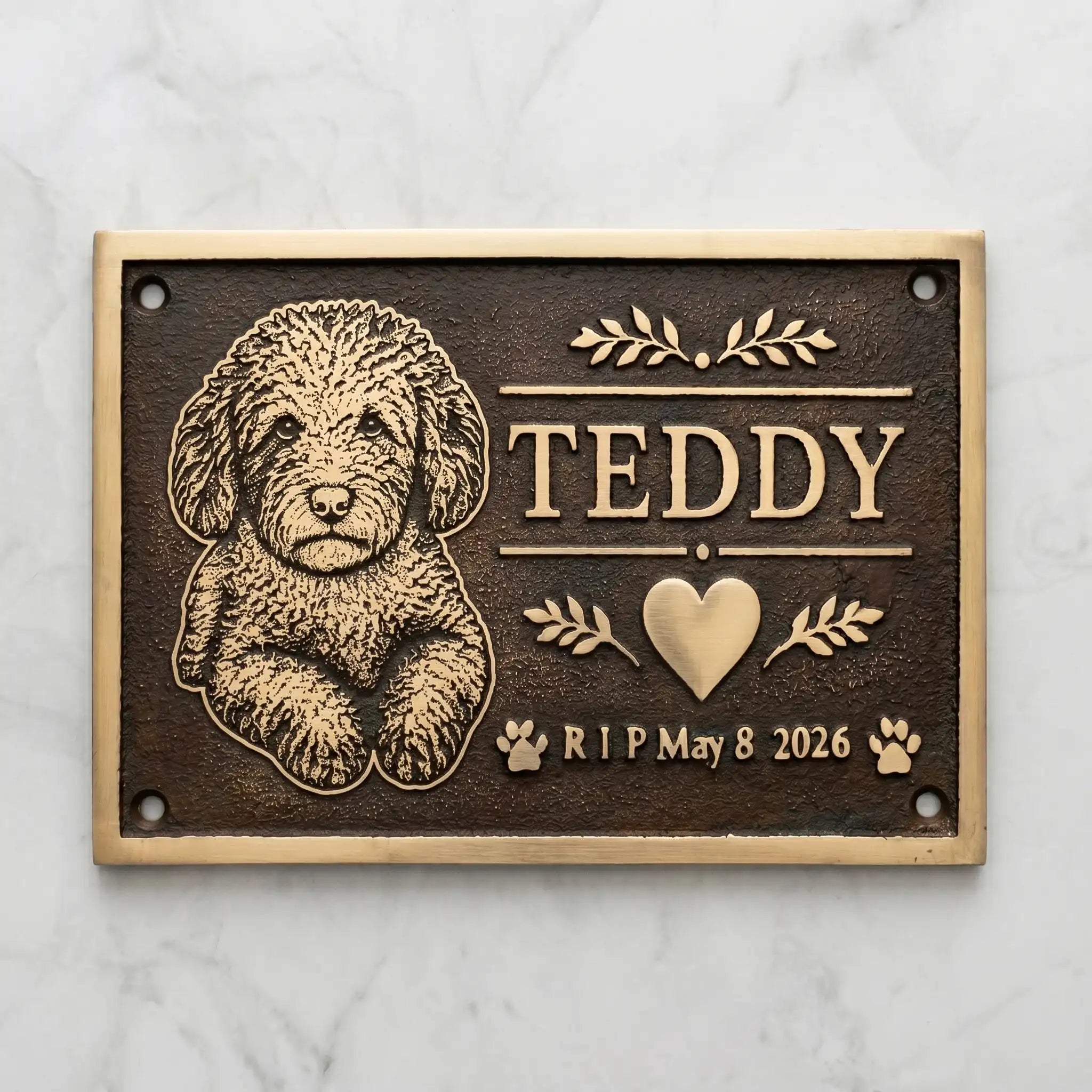 Bronze Memorial plaque for a dog named Teddy with engraved text and illustrations on a marble background