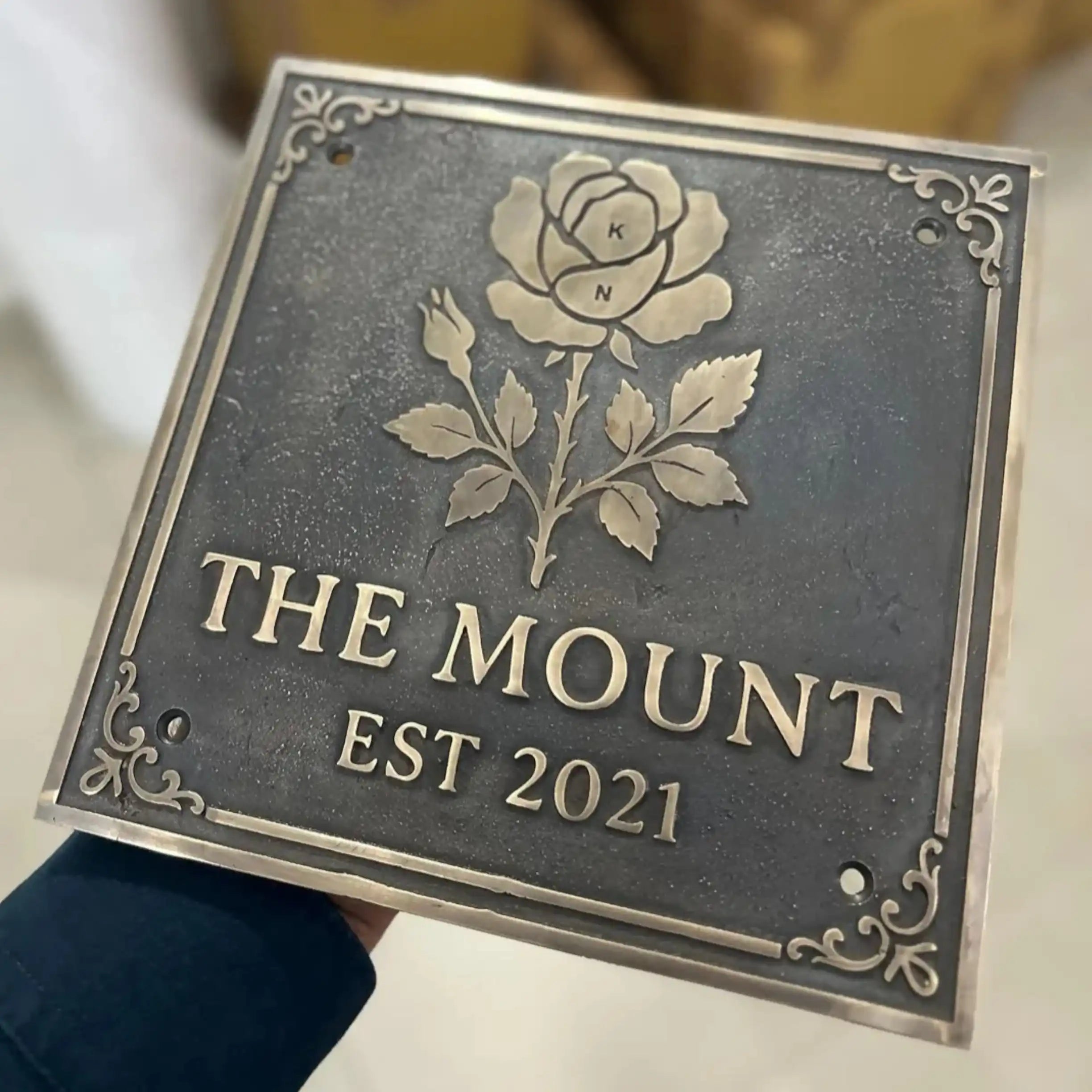 Decorative Bronze sign with rose design and 'The Mount Est 2021' text