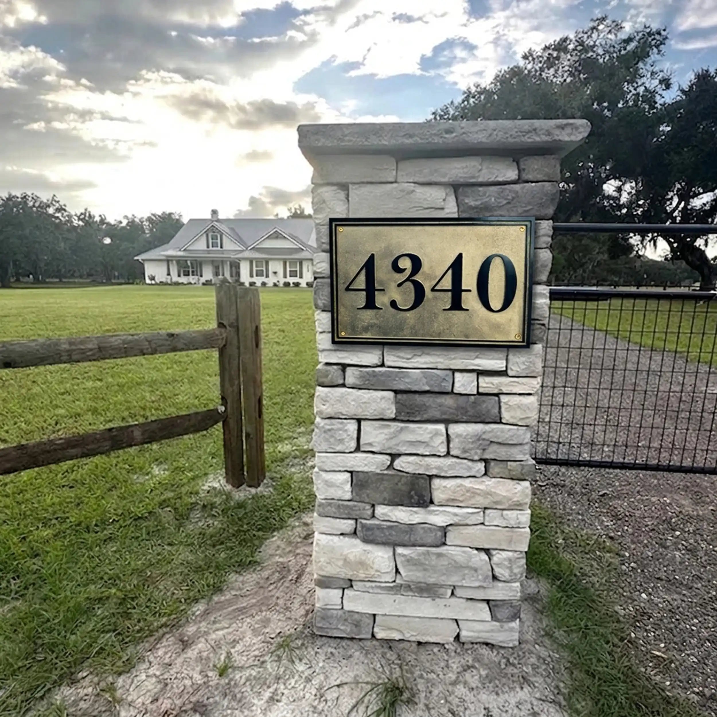 Stone pillar with house number 4340 in a rural setting with a house and fence in the background.