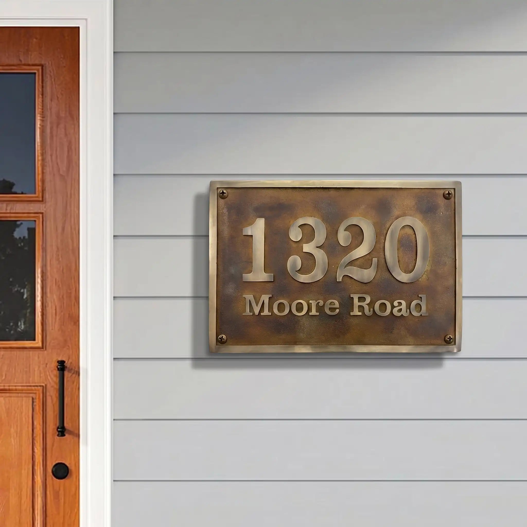 House number sign '1320 Moore Road' on a gray wall next to a wooden door.
