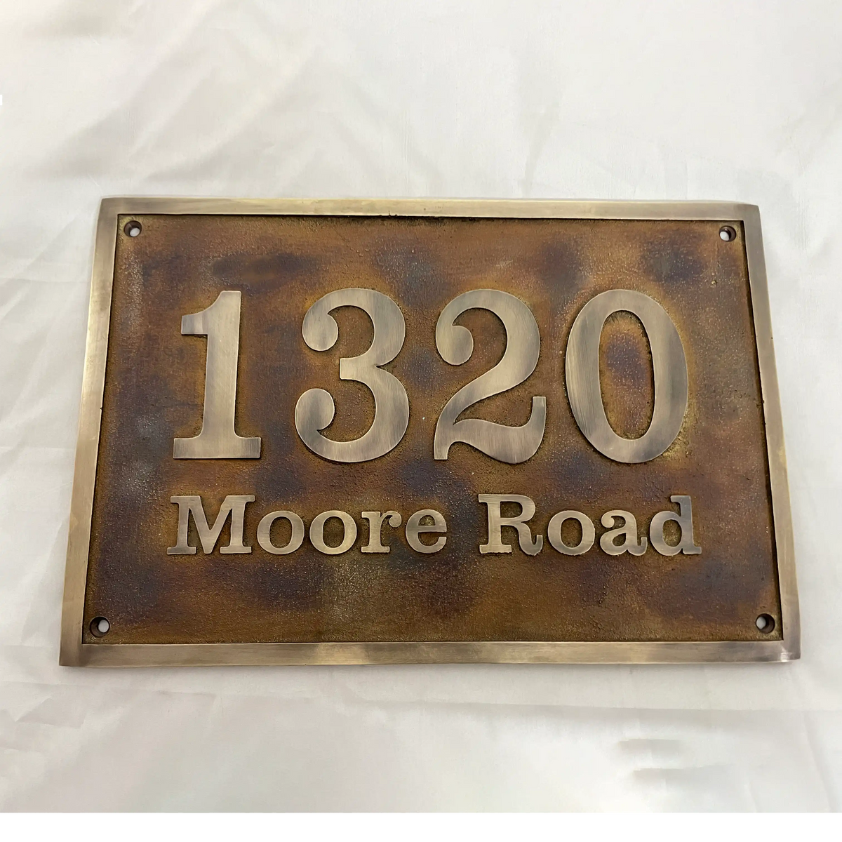 Bronze house number sign with '1320 Moore Road' on a white background