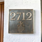 Meta house number plate with '2712' and a coat of arms on a white wall.