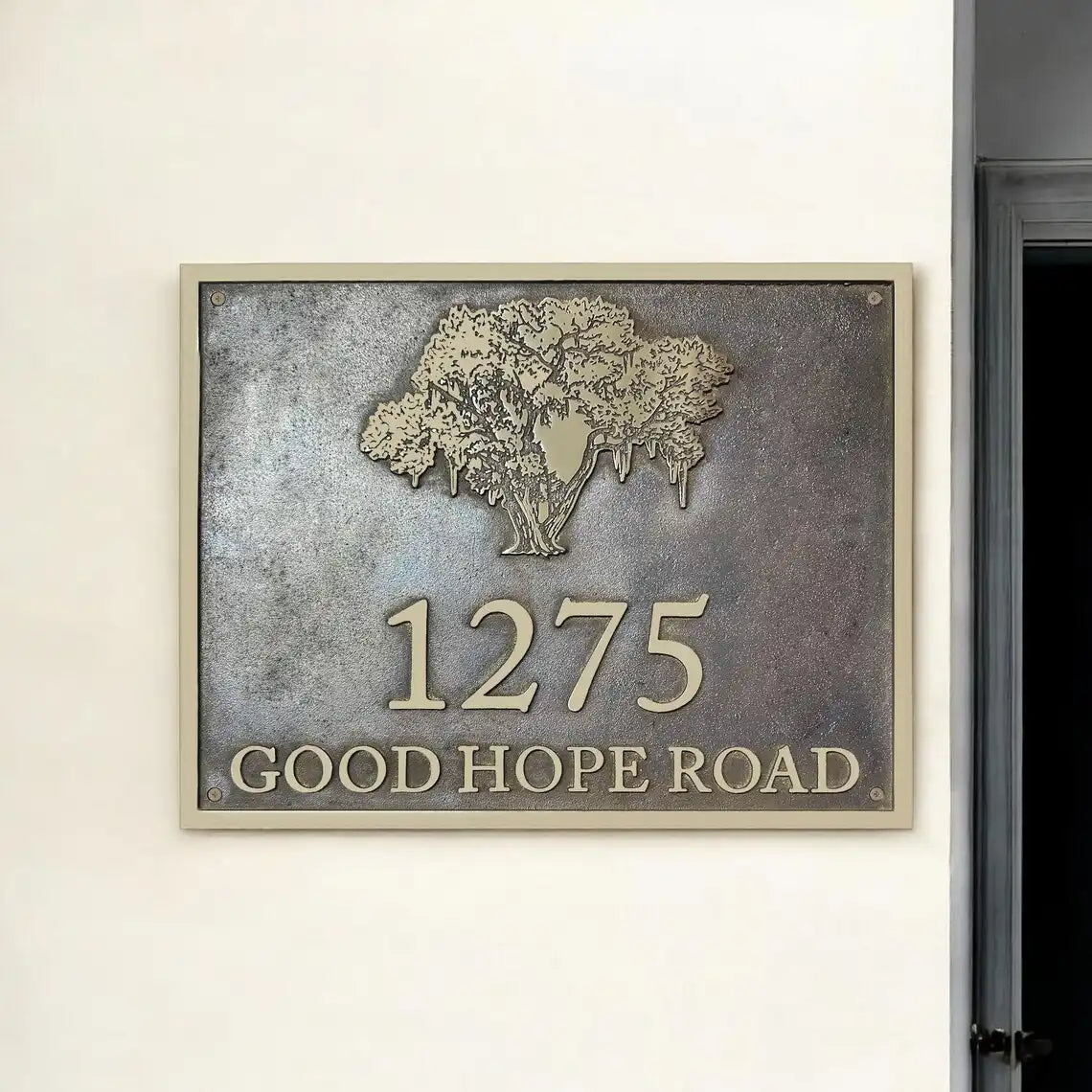 Bronze house number sign with tree design on a metallic background