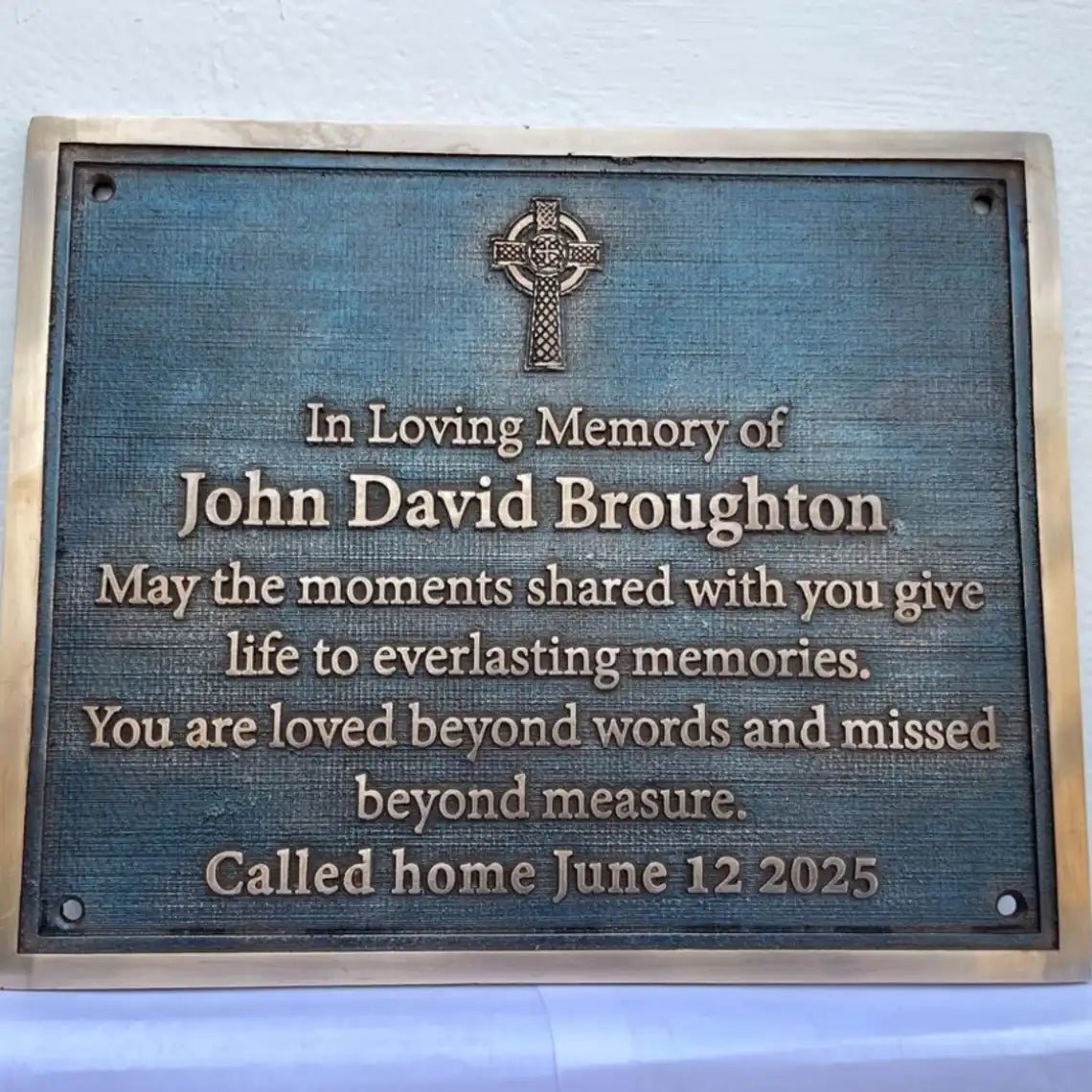 Memorial plaque for John David Broughton with Celtic cross design on a blue background.