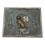 Bronze plaque with a bear emblem, trees, and 'Est. 1929' text on a white background