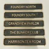Set of bronze nameplates with gold text on a white background