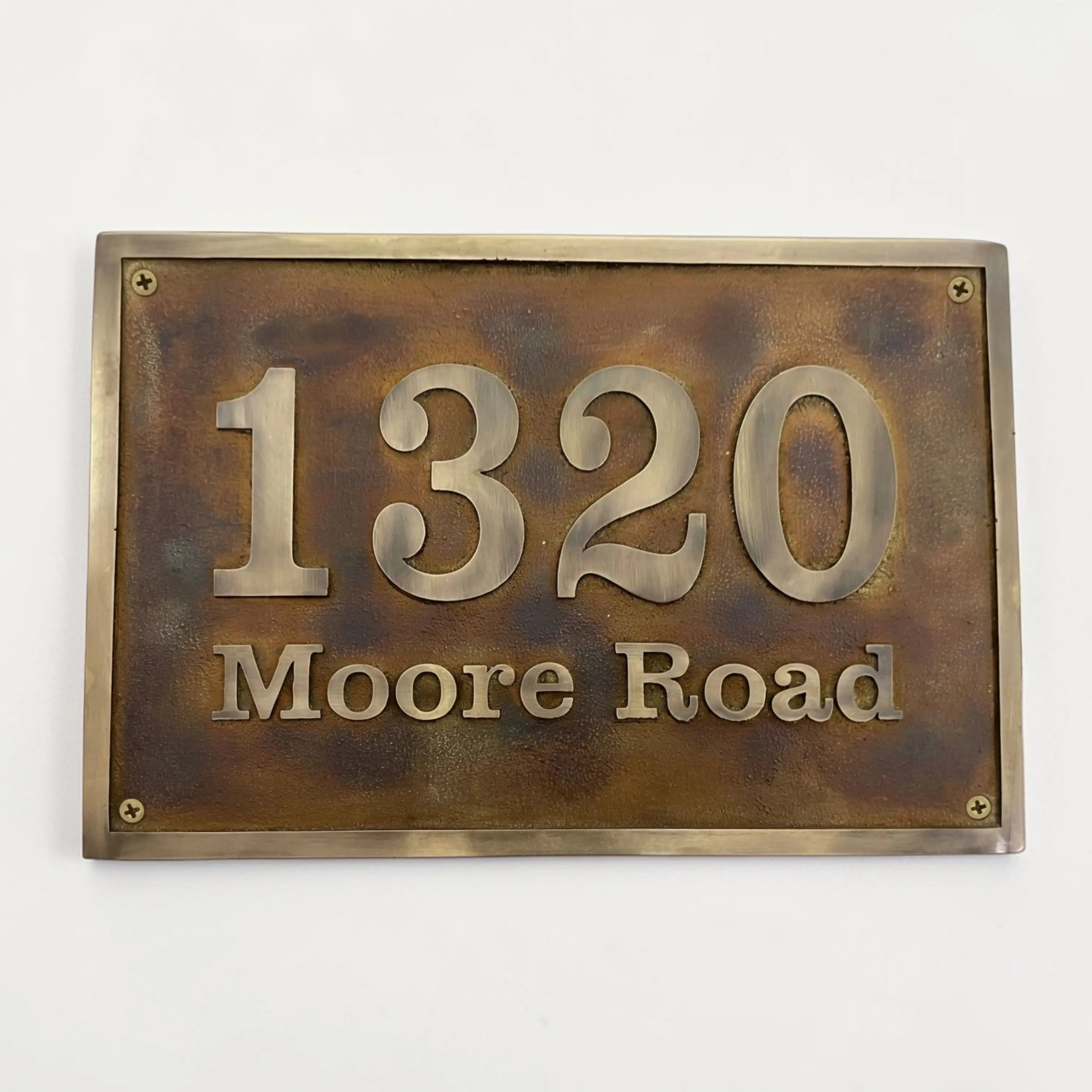 Bronze house number sign with '1320 Moore Road' on a white background