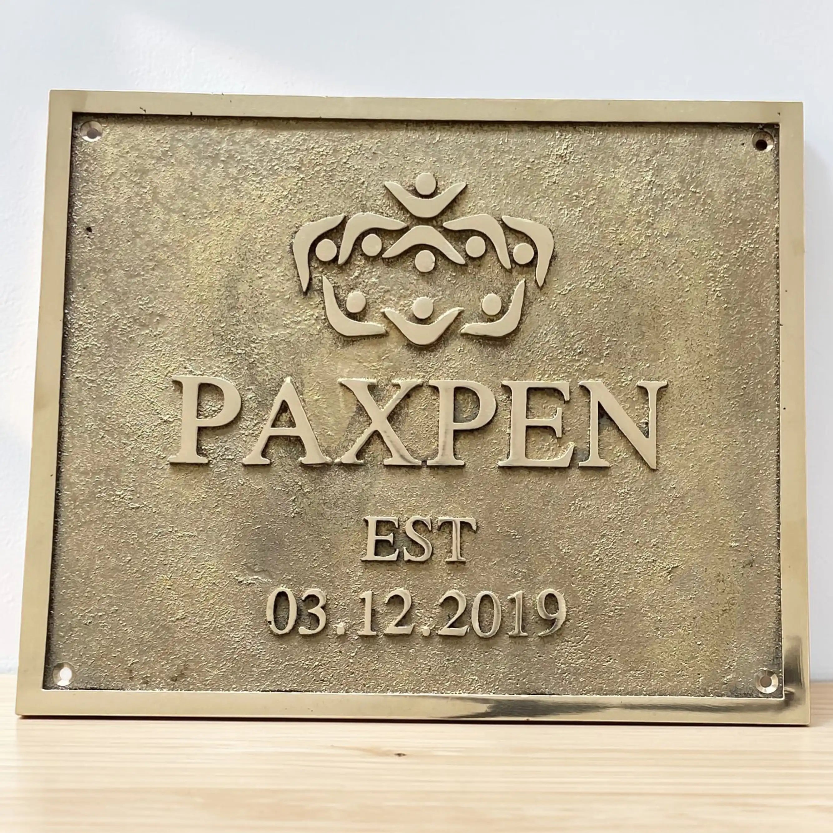 Cast Bronze/Brass custom signs & plaques - Brass plaque with 'PAXPEN' logo and establishment date on a white background