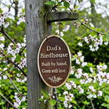 Cast Bronze sign on a tree branch with 'Dad's Birdhouse' text and floral background