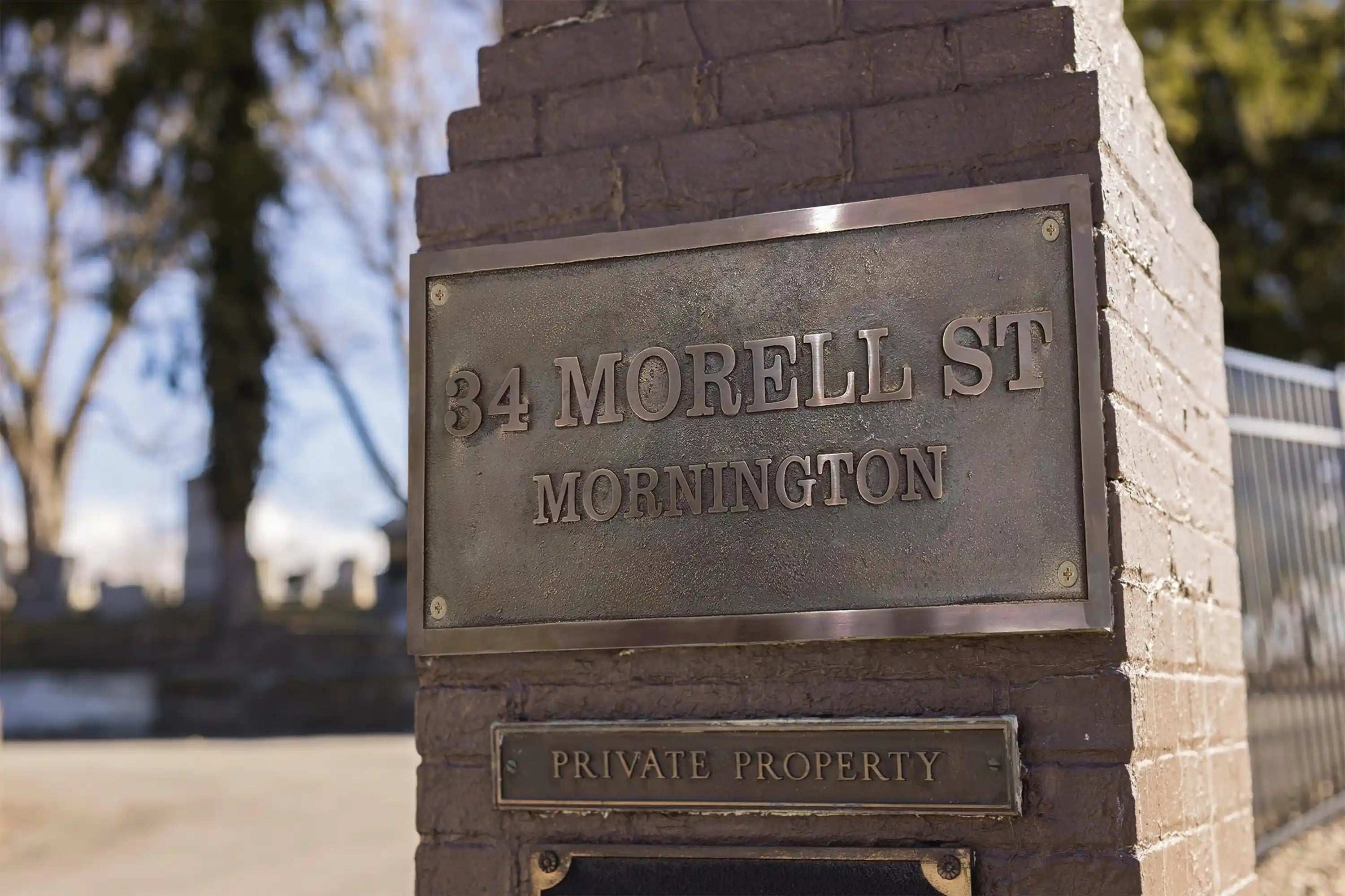 Bronze plaque with address '34 Morell St, Mornington' on a stone pedestal.