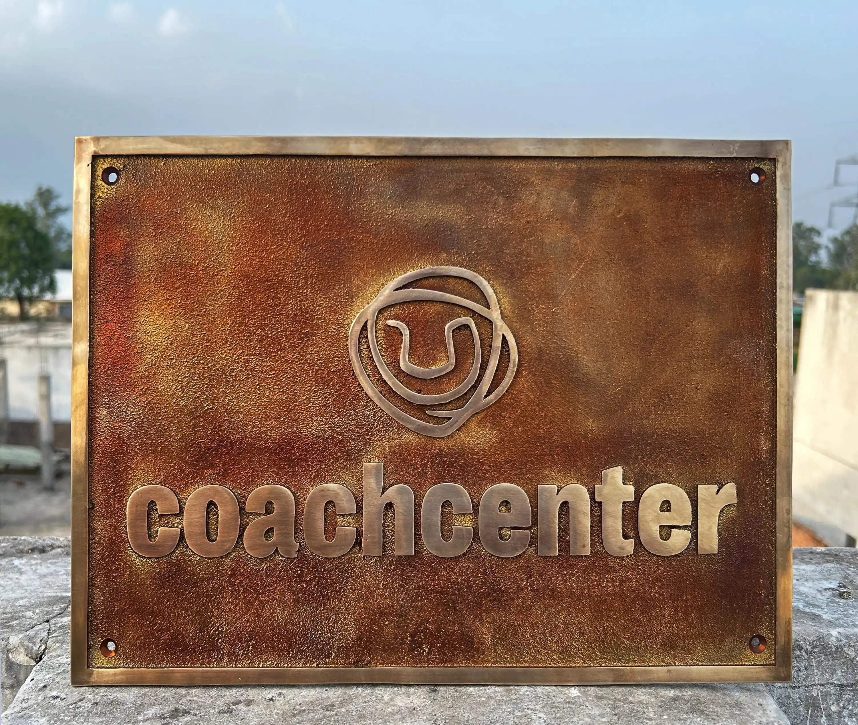 Rust-colored sign with 'coachcenter' logo on a stone surface