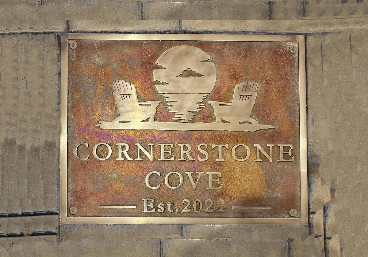 Metal sign with 'Cornerstone Cove' and establishment year on a stone wall.