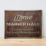 Bronze plaque with 'iThrive Christian Church' and 'Mainer Hall' text on a wooden surface.