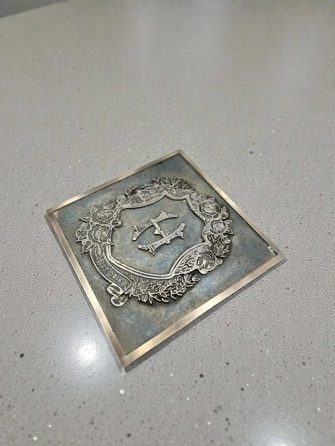 Decorative bronze metal plaque with emblem on a gray surface