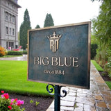 Sign for 'Big Blue' with a building and garden in the background