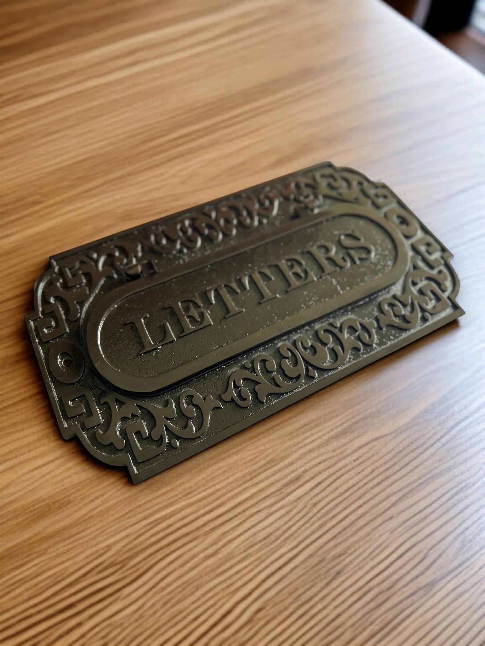 Decorative metal letter box on a wooden surface