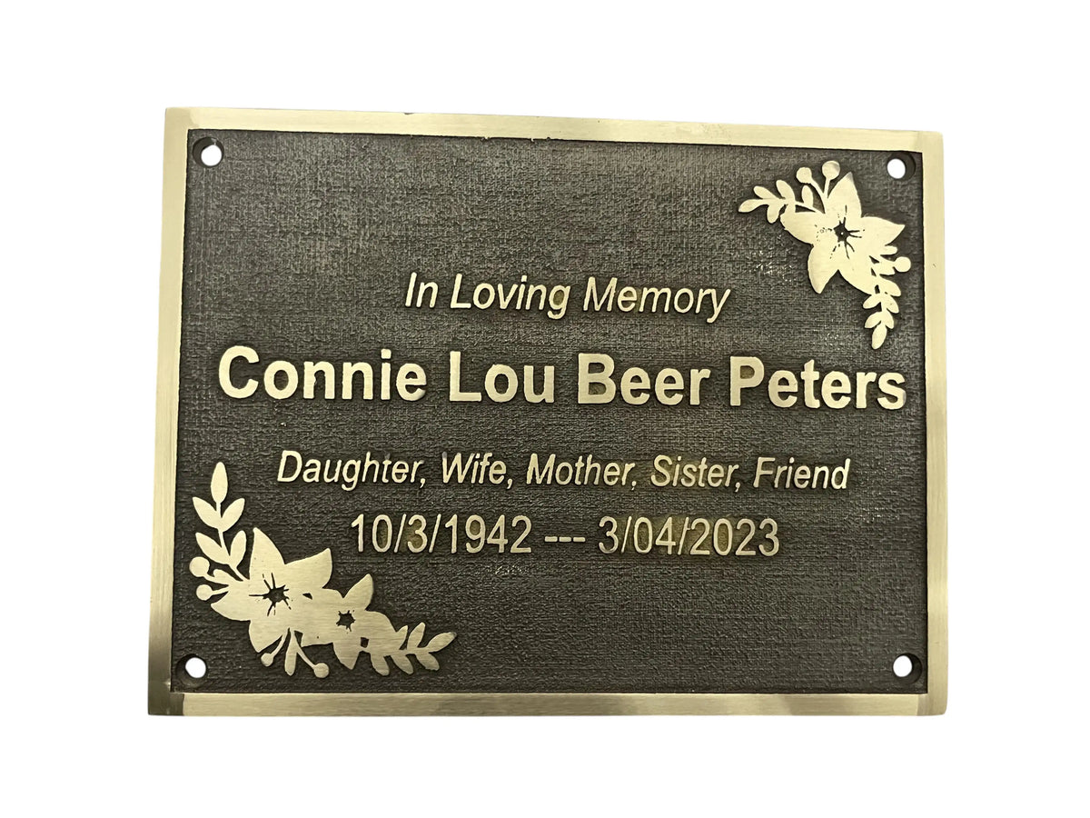 Memorial plaque with engraved text and floral designs on a white background