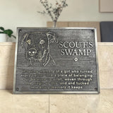 Memorial plaque for a dog named Scout's Swamp with engraved text on a wooden surface.