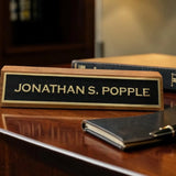 Nameplate with 'Jonathan S. Popple' on a wooden surface with a pen and notebook.