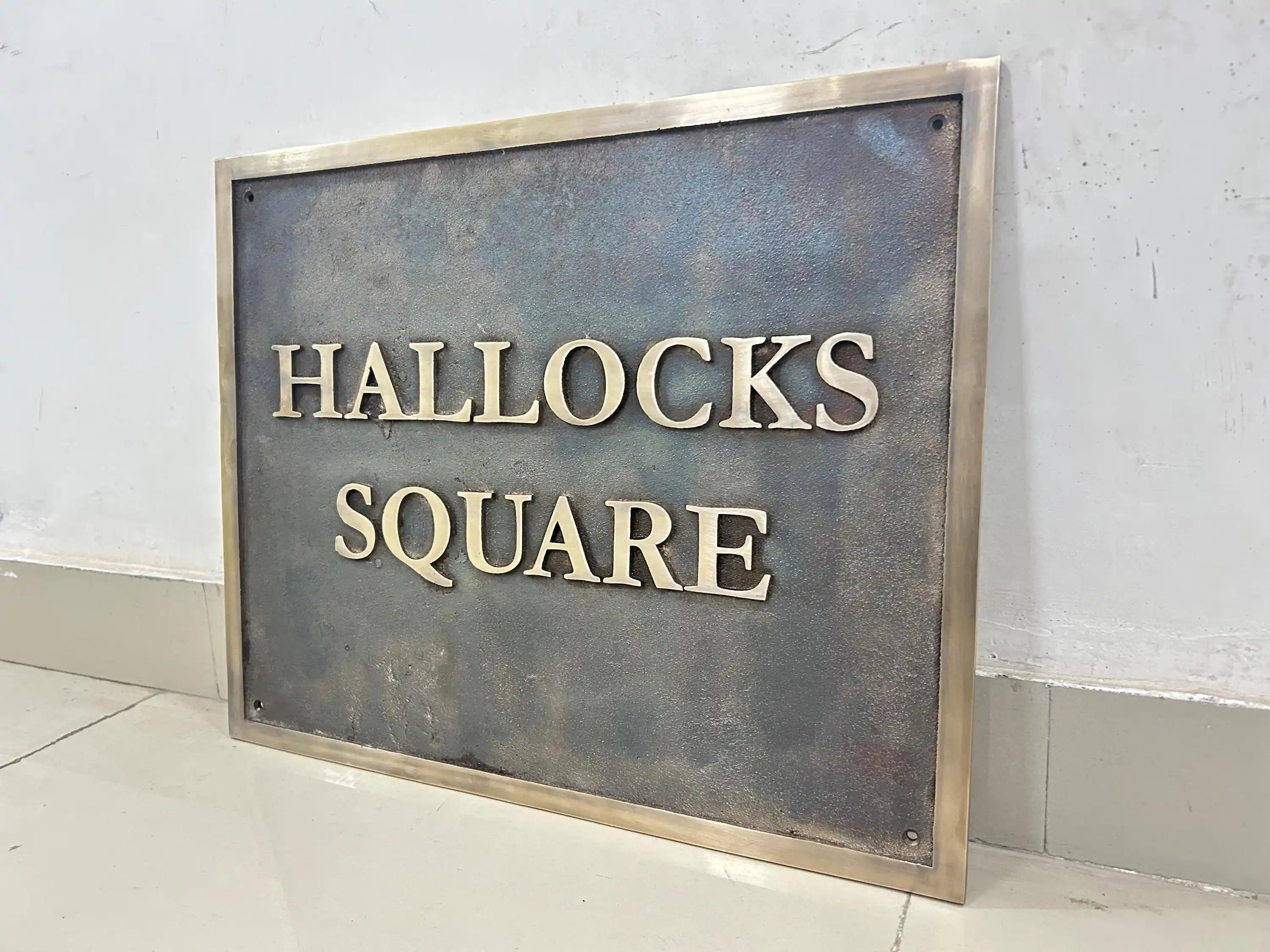 Metal sign with 'HALLOCKS SQUARE' text on a plain background