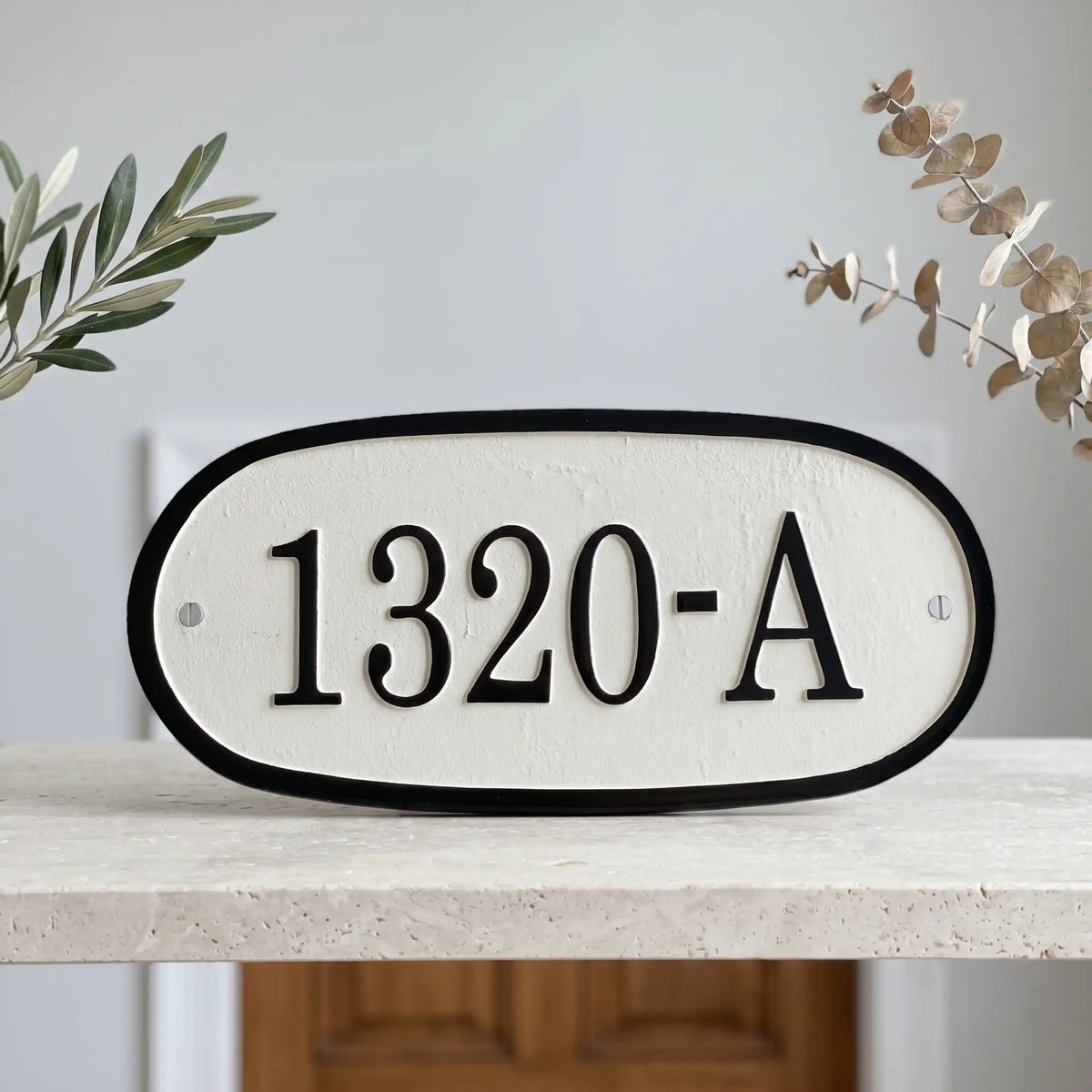 Personalized cast bronze address sign with raised letters House number sign '1320-A' on a white background with decorative elements.
