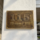 Bronze house number plaque on a white wall