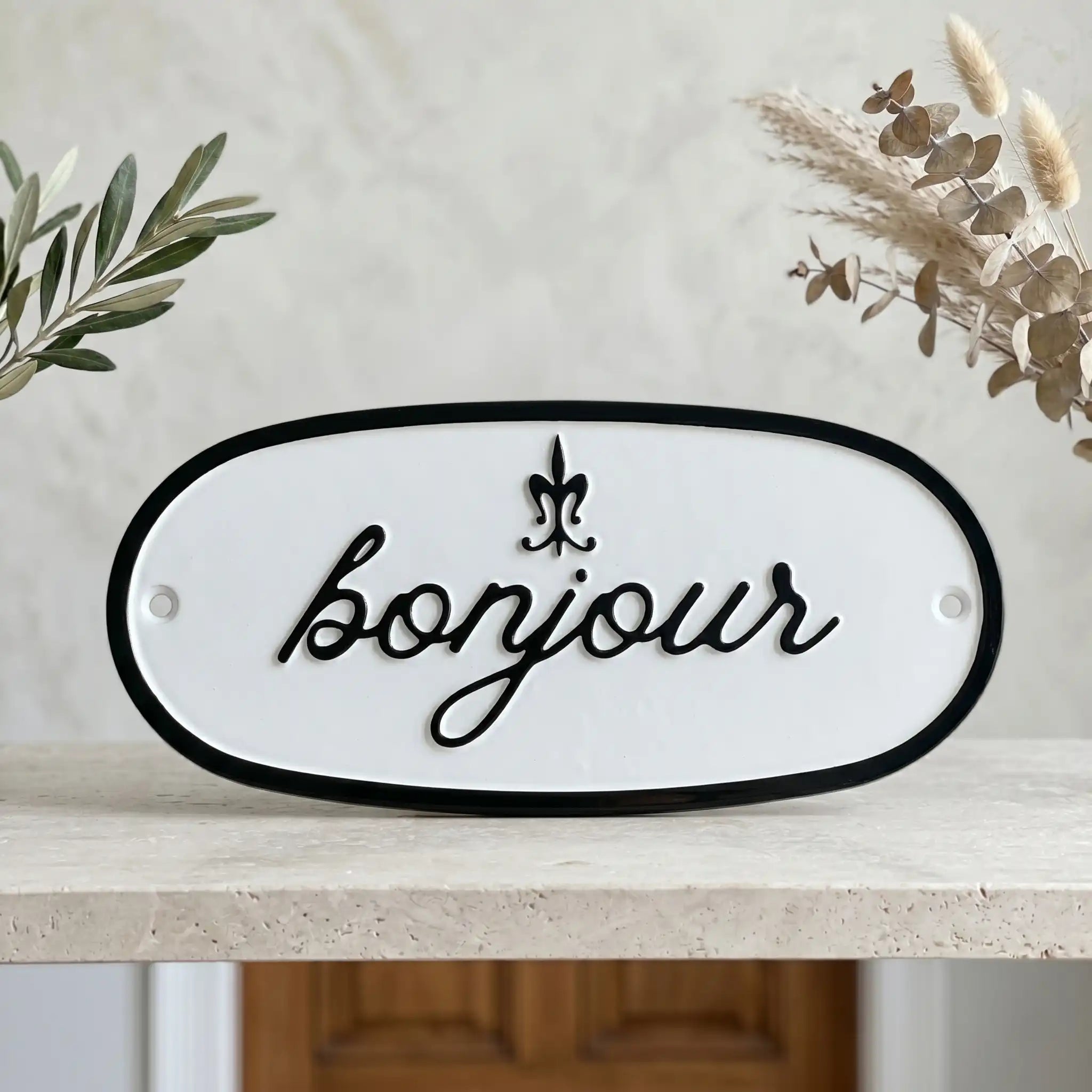 Address sign with 'bonjour' text on a shelf with plants