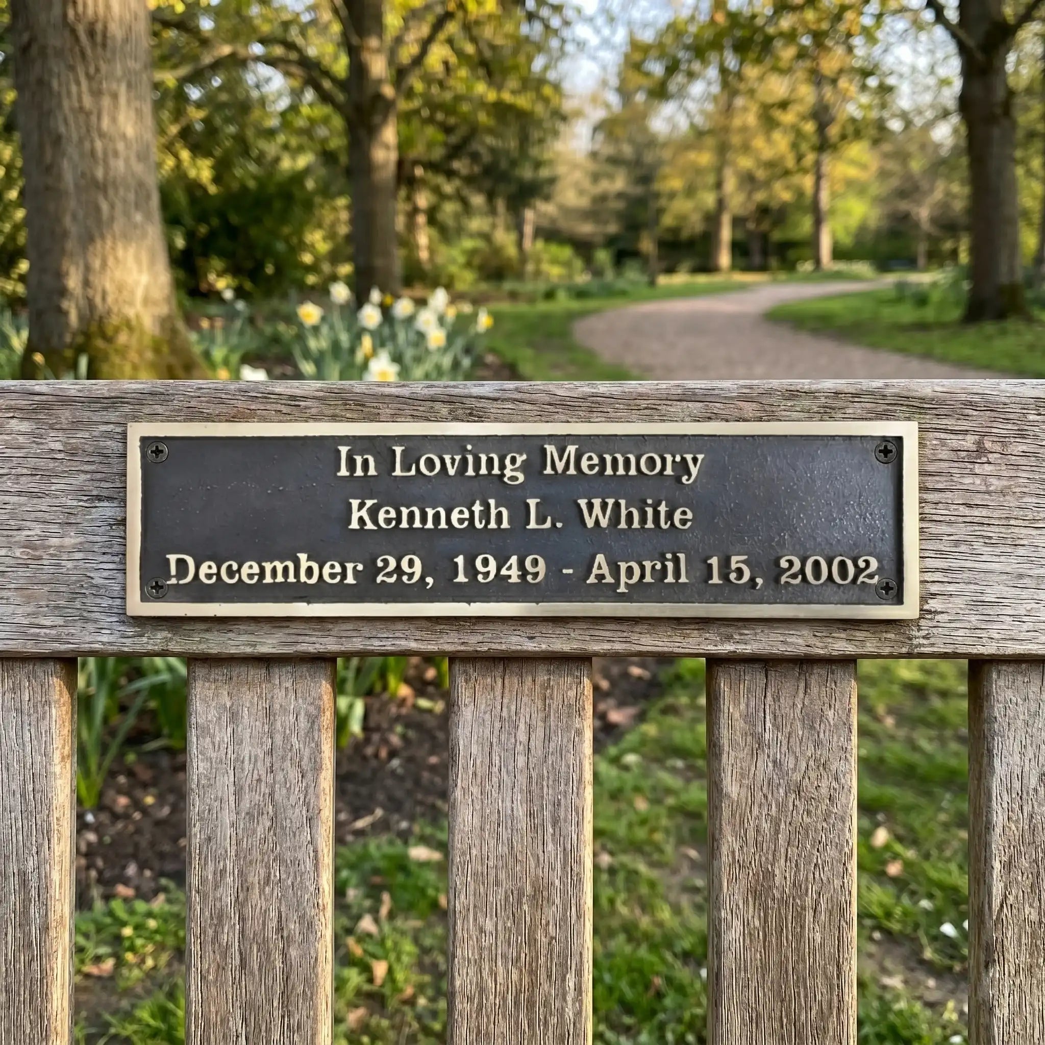 Bench Memorial plaque for Kenneth L. White in a park setting with trees and flowers.