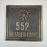 Cast bronze house number plaque - Metallic house number sign with '552 LUMBER LANE' on a textured wall.