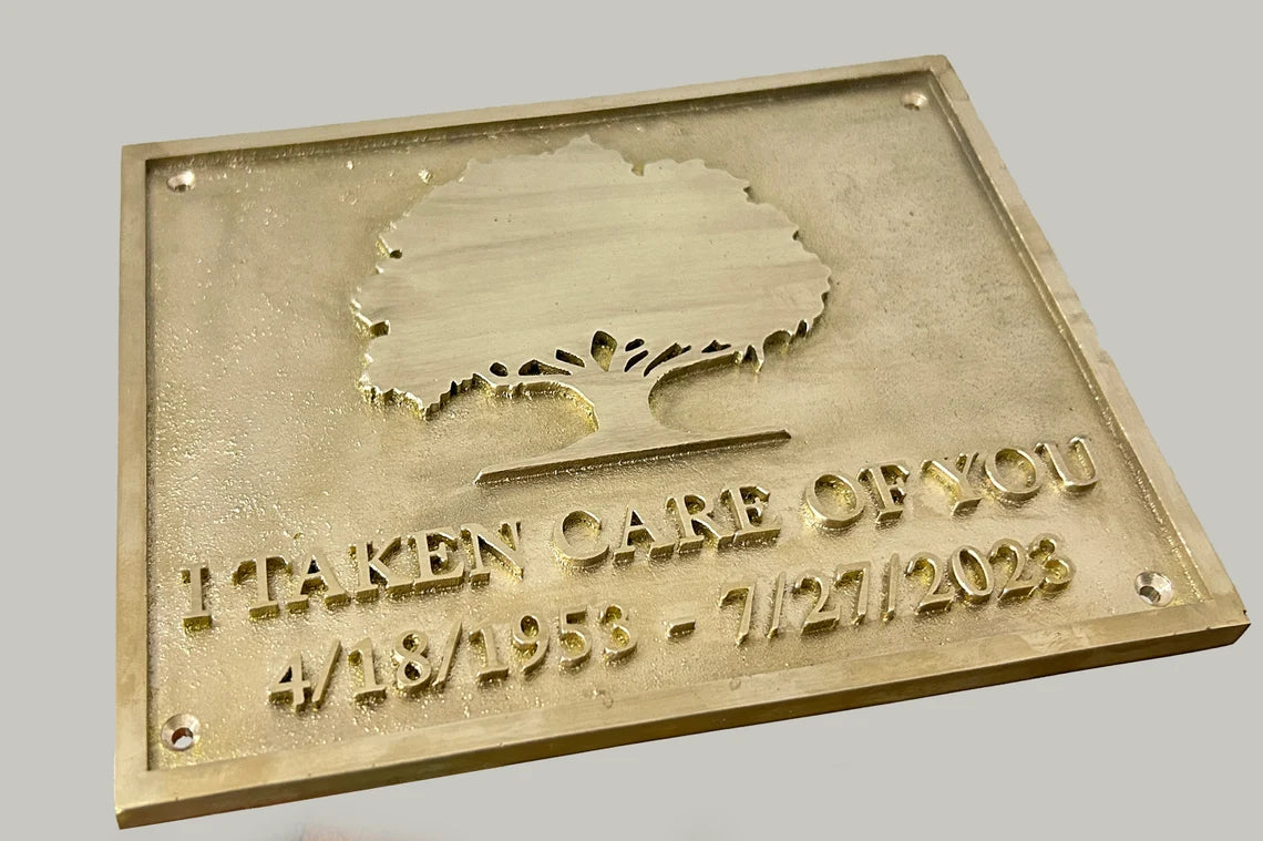 Brass plaque with engraved text and tree design on a gray background