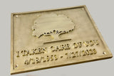 Brass plaque with engraved text and tree design on a gray background