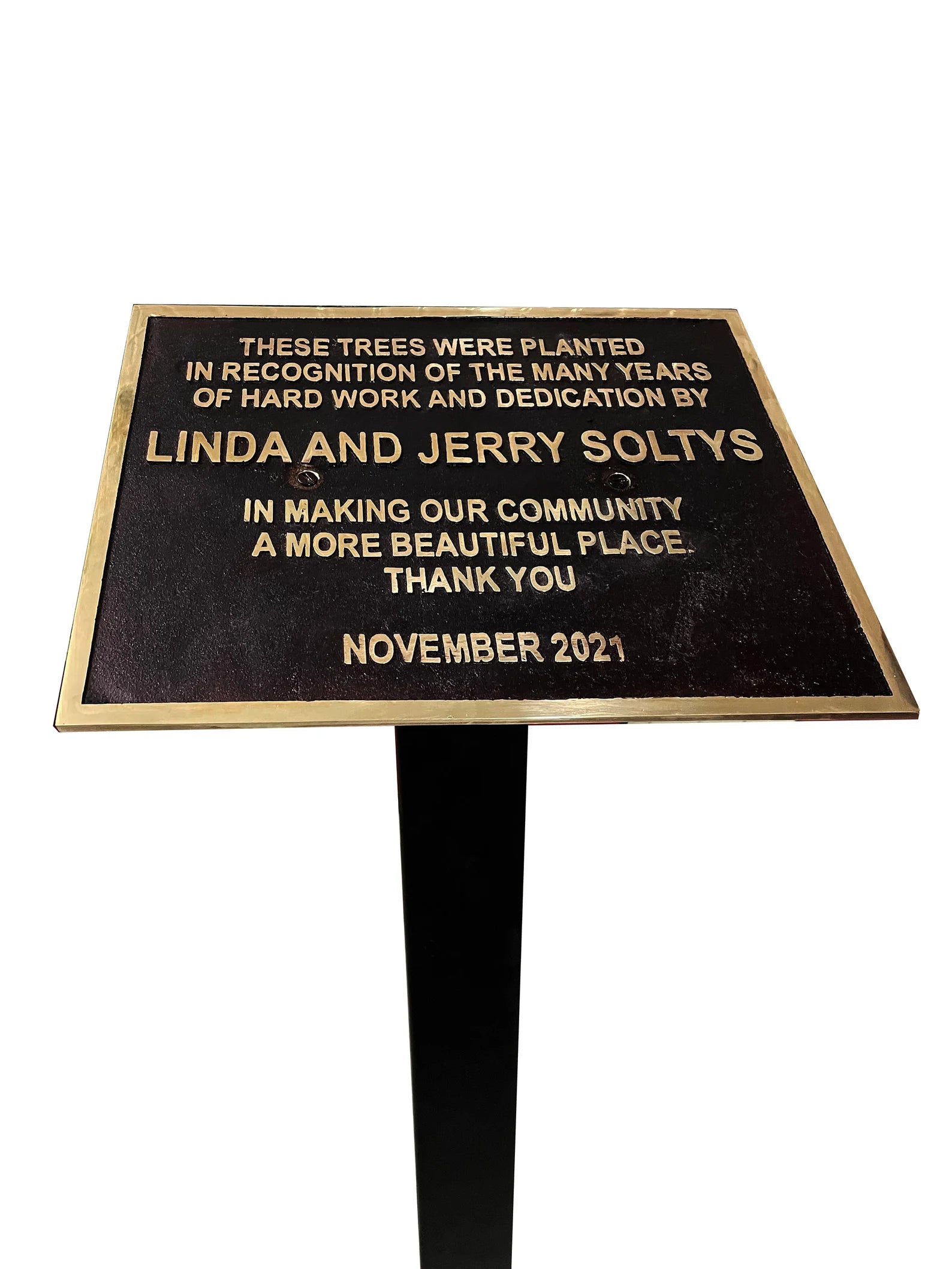 Plaque on a stand with engraved text recognizing Linda and Jerry Soltys for their community dedication.