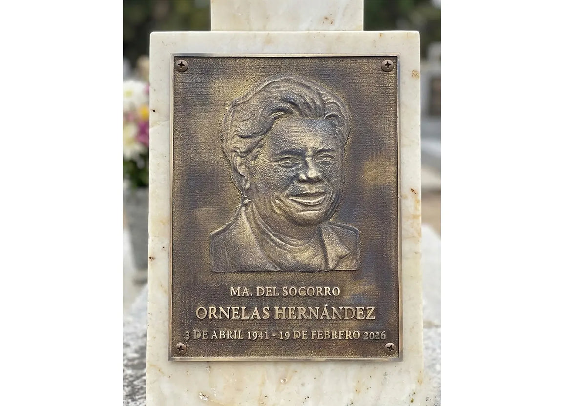 Bronze plaque with a portrait and engraved text on a marble base.