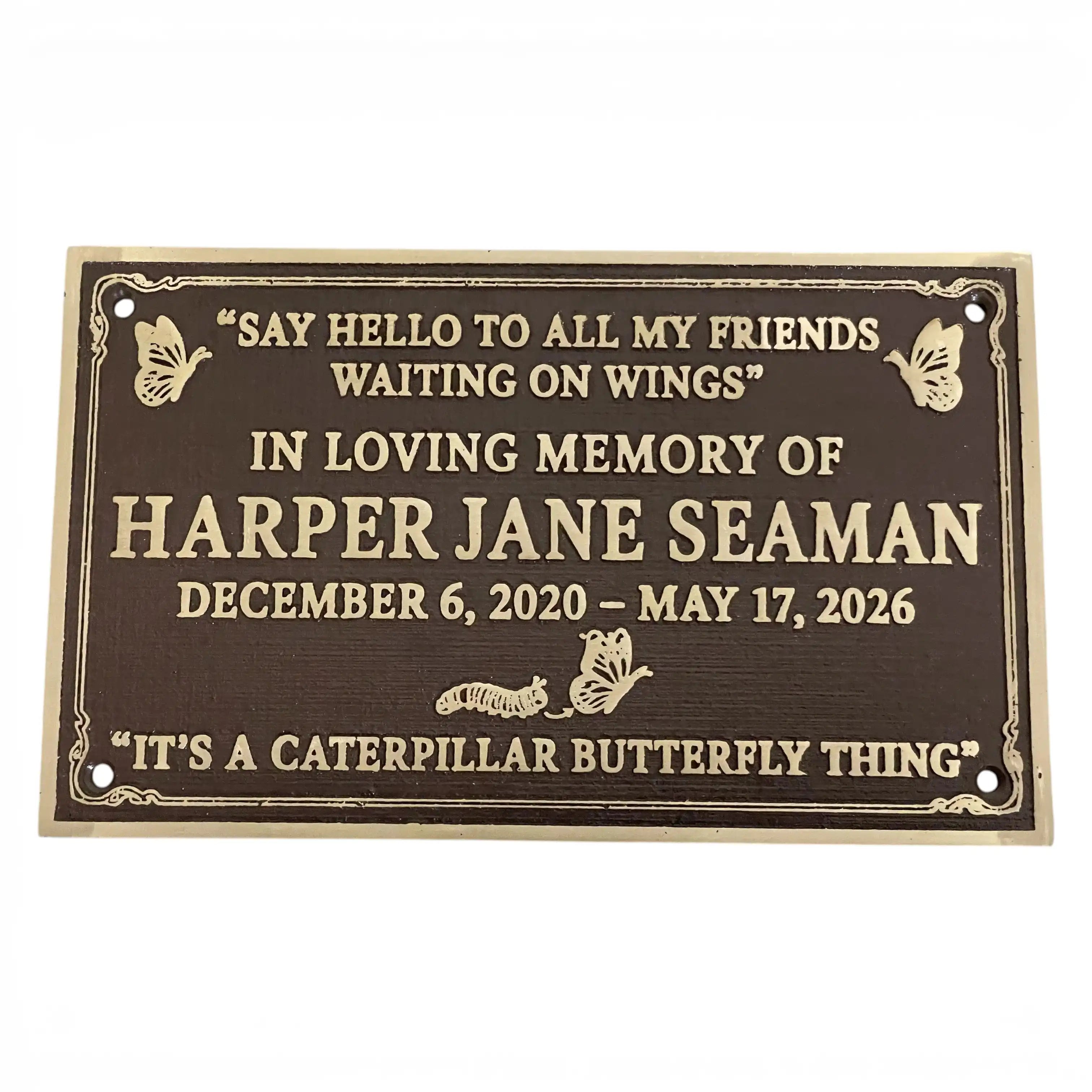 A rectangular dark brown memorial plaque with gold lettering and butterfly illustrations, reading a remembrance message for Harper Jane Seaman with dates and quotes, shown on a plain white background.