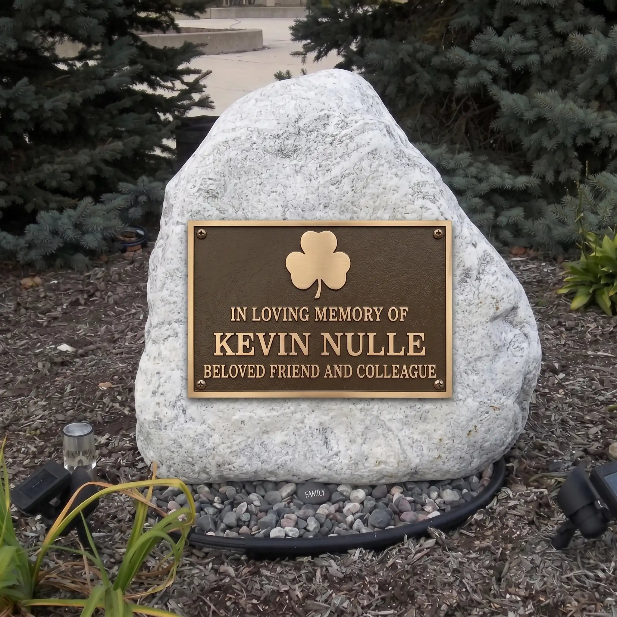 Memorial bronze plaque with a stone honoring Kevin Nulle in a garden setting.